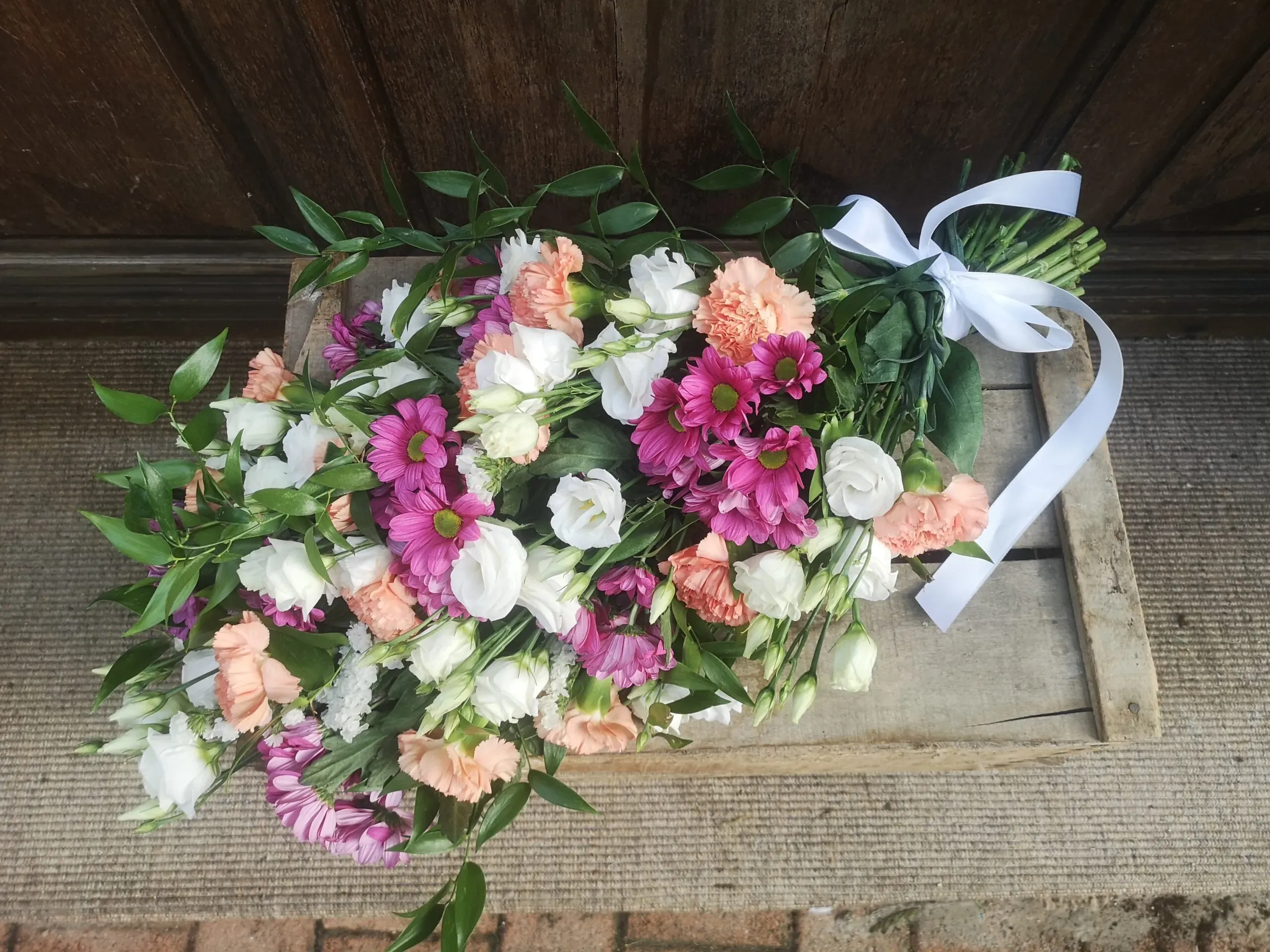 Magnifique bouquet de deuil avec fleurs variées et ruban blanc, hommage.