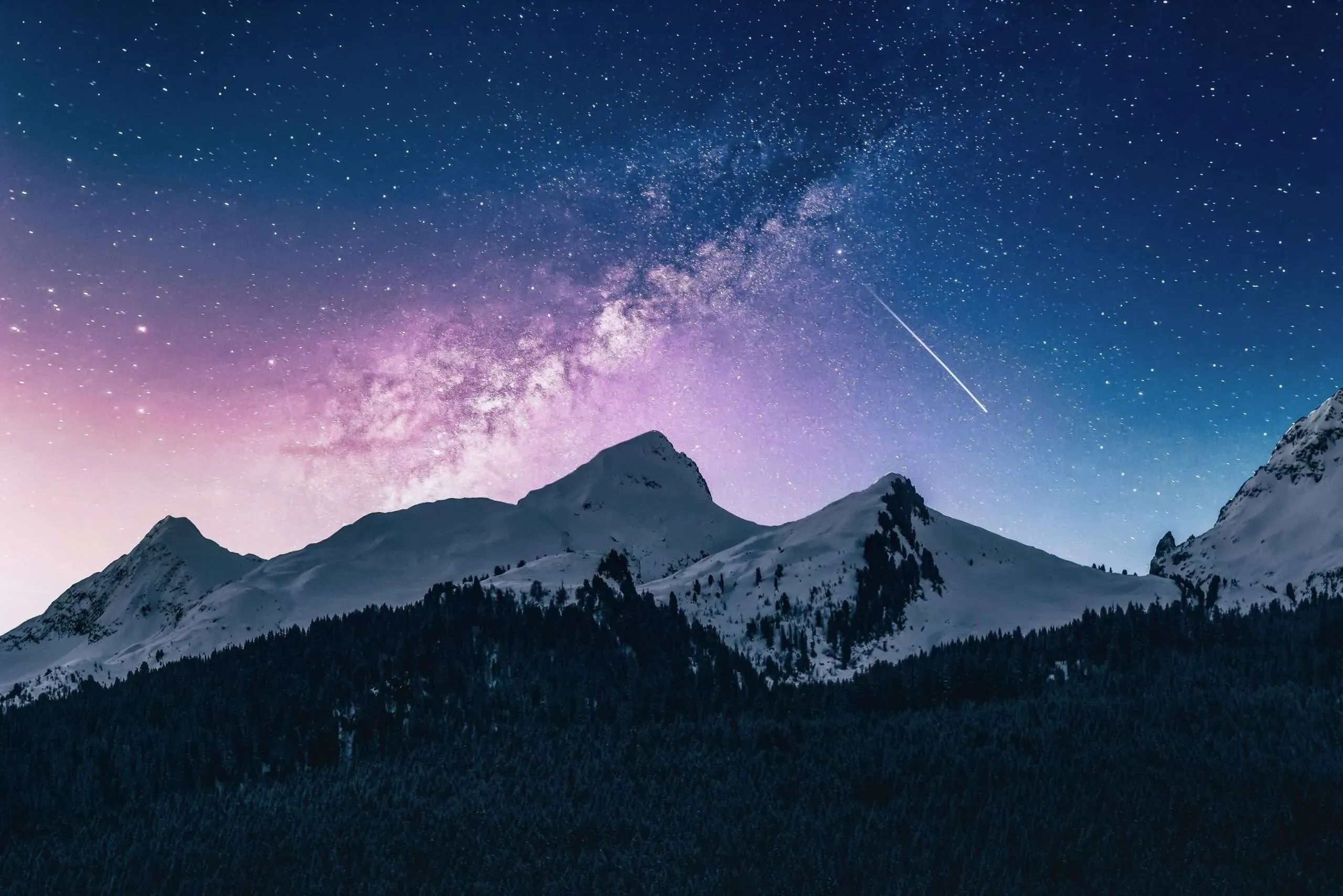Ciel nocturne étoilé et Voie lactée au-dessus de montagnes enneigées.